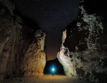 Person shining a flashlight in between two large cliffs
