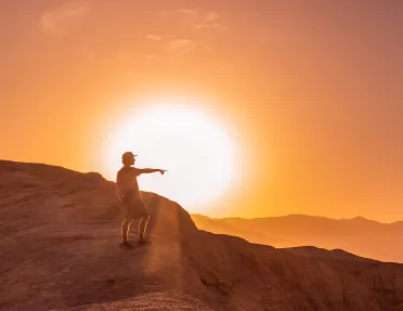 Person standing on a cliff with the sunset in the background