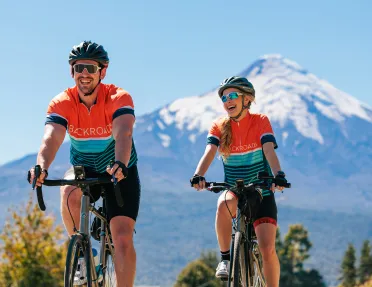 Man and woman riding bikes with views of large mountains in the distance