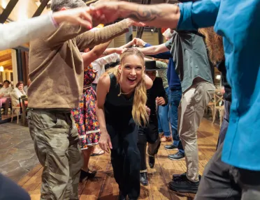 Woman walking under a group of people with their arms sticking out
