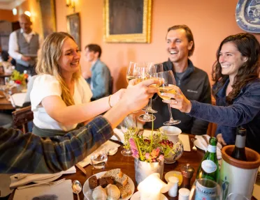 Group of people at a dining table raising their wine glasses