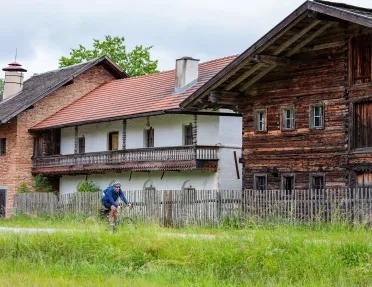 Man riding a bike on an empty road with wooden houses in the background