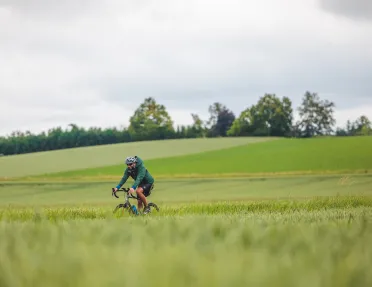 Man riding a bike on a road next to an empty valley of grass