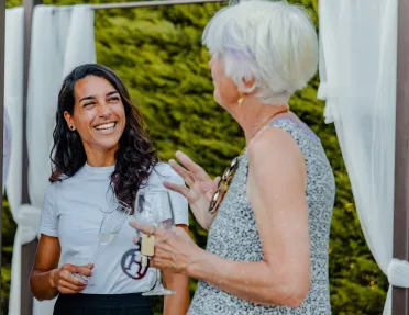 Two women smiling and talking, while holding glasses of wine