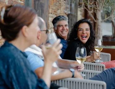 Group of people smiling and laughing while holding wine glasses
