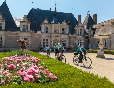 Group of people riding bikes in front of a castle building