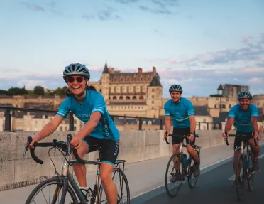 Two men and one woman riding bikes on a road with a town in the background