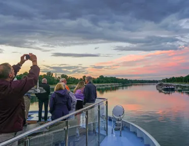 Group of people on a glass ledge looking at a sunset