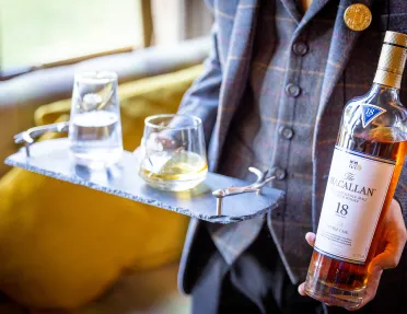 Man holding a bottle of whisky and two glasses