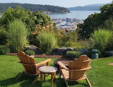 Two wooden chairs in an outdoor garden, overlooking boats and a large lake