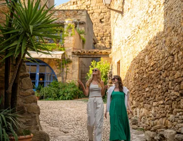 Two women smiling while walking through a stone alleyway