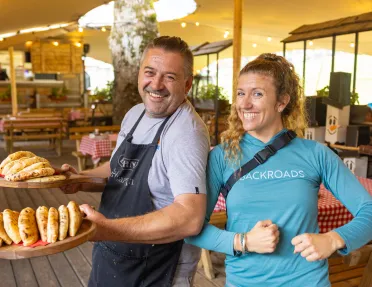 Woman smiling with a man wearing an apron, holding two plated full of baked bread