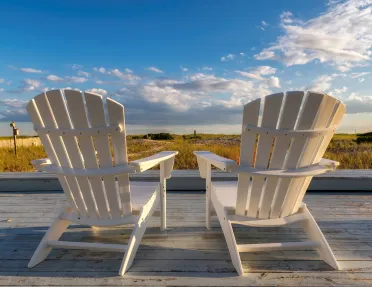 Two white chairs on an outdoor patio, looking out to a large valley