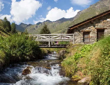 Small river under a wooden bridge attached to a stone building