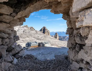 Large stone archway with a building in a gravel area