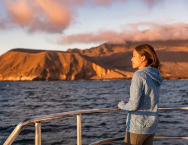 Woman standing on a boat, looking out to the ocean