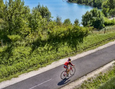 Person riding a bike on a road with a lake in the background