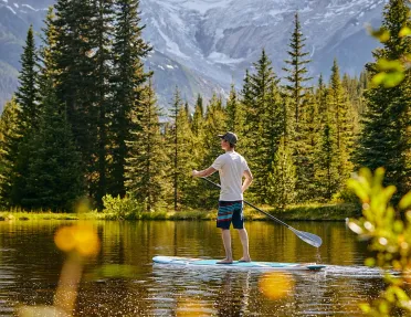 paddleboarder on a calm lake surrounded by trees