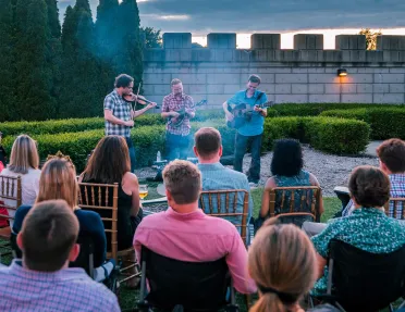 Group of people sitting and watching a small band play outdoors