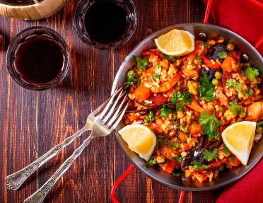 Bowl of paella with cut lemons on the sides
