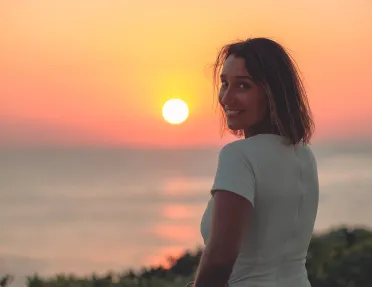 Woman looking back and smiling with the sunset in the background