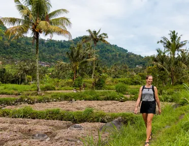 Woman smiling while walking on a field of grass and crops