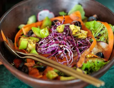Bowl of vegetables and cabbage, with a salad dressing on top