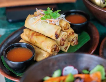 Plate of fried eggrolls with a bowl of red sauce