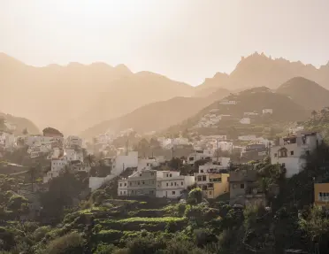 Town of white houses on a grassy hill, with the foggy sunlight in the background