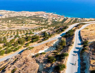Long, empty roads with people biking, with the ocean in the distance