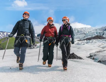 Three people wearing snow gear, walking through a icy trail