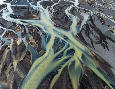 Large rivers of green water cutting through the sand at a beach