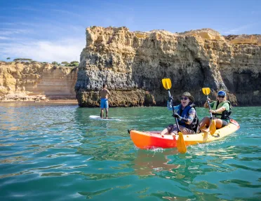 Two women laughing while paddling on a kayak