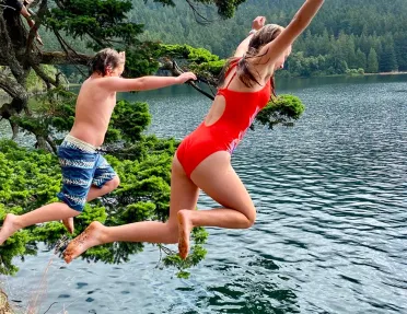 Man and woman jumping off a cliff into a lake