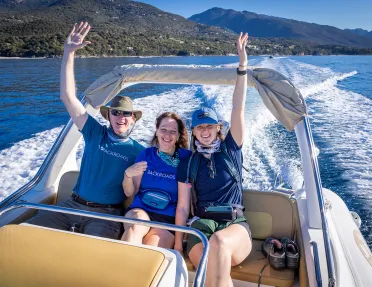 Three Backroads guests put their hands in the air on the back of a boat