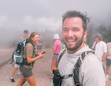 Group of people smiling while walking through a foggy trail