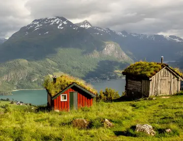 Red building on top of a cliff with a lake in the distance