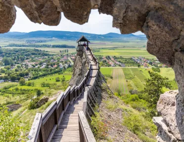 Large wooden pathway on top of a hill, overlooking a large grass valley and a small town