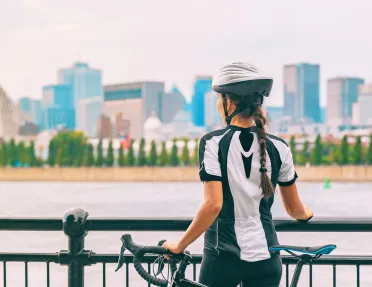Woman standing next to her bike, looking out to a city and a river