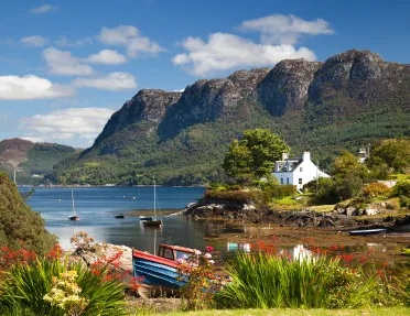 Lake with boats by the shore, and large mountains in the background