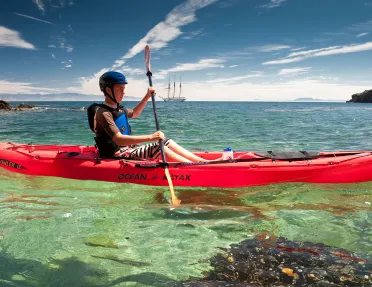 Man paddling on a red kayak in the ocean