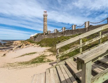Beach with a wooden staircase and a lighthouse in the background
