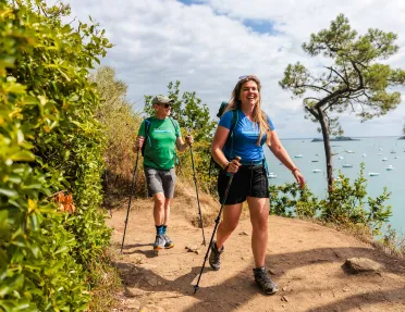 Man and woman smiling while walking through a dirt trail