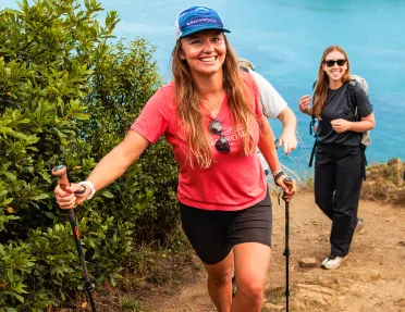Two women with walking poles ascending a sandy path