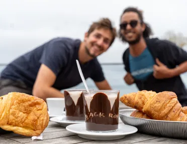 Two people behind a table full of chocolate desserts and croissants