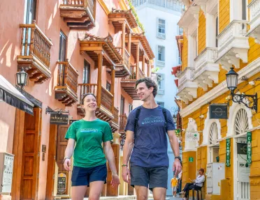 Man and woman walking in an alley surrounded by tall apartment buildings