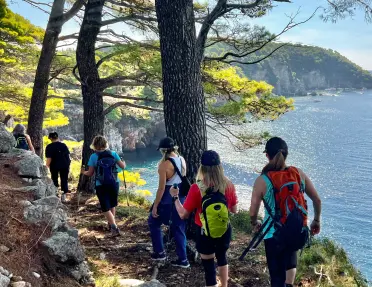 Group of women hiking on a dirt trail by a lake