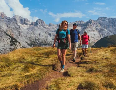 Women and two men hiking on a dirt path on top of a hill