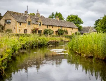 Exterior view of beige brick building with a river in front