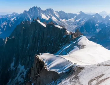 Top view of snowcapped mountains with larger mountains in the distance
